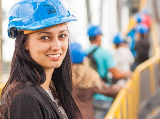 Young woman has a blue hard hat on at a construction site